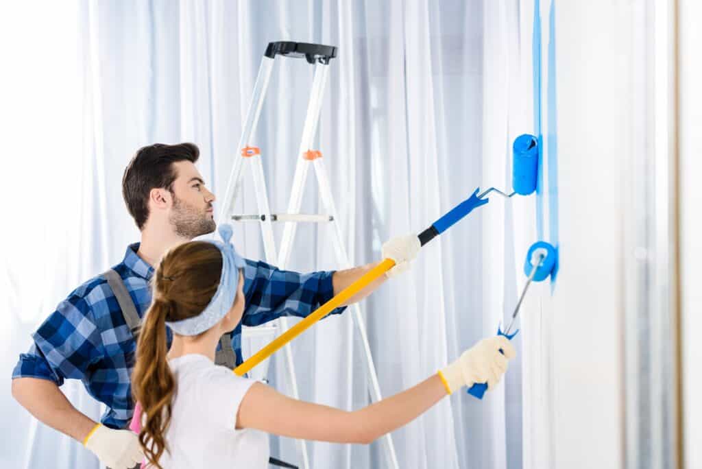 boyfriend and girlfriend painting wall with blue paint