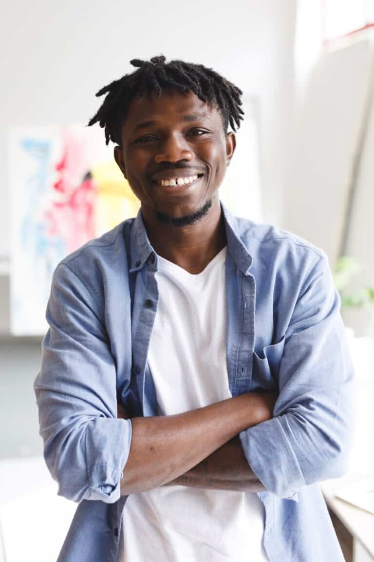 Portrait of smiling african american male painter at work looking at camera in art studio